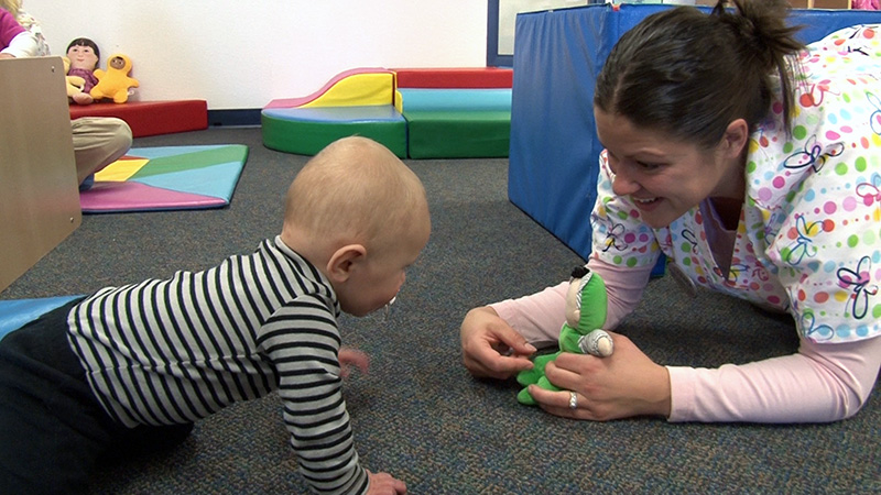 An infant crawls toward a caregiver