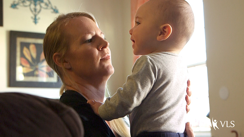 A caregiver holds up a smiling toddler